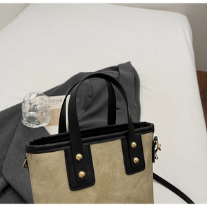 Détail du sac en toile kaki avec bordure en cuir noir et rivets métalliques dorés