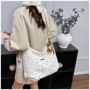 Detail of a beige corduroy tote bag with bow patterns and cute plush bear charm