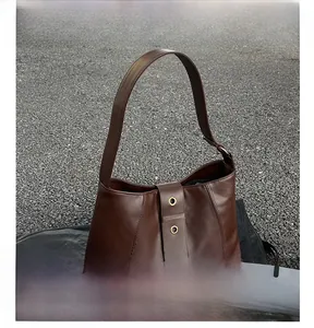 Macro detail of brown leather hobo bag featuring vintage rivets and gold metal eyelets