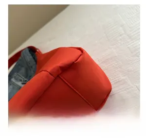 Détail des coutures plates d'un sac cabas en nylon rouge avec insert en jean bleu