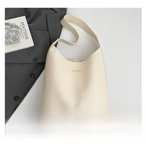 Close-up of cream tote bag with gold fashion text beside aesthetic props and blazer