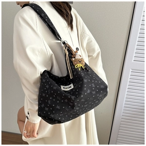 Detail of black corduroy tote bag with heart prints and cute bear plush charm