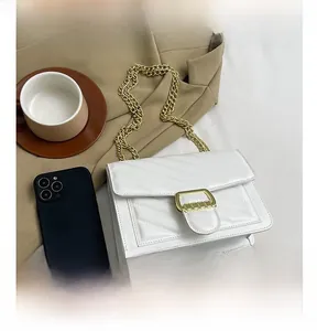 Detail view of white quilted chain bag with herringbone pattern and golden square buckle