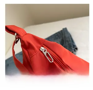 Détail du sac cabas en nylon rouge avec fermeture éclair en métal argenté et coutures