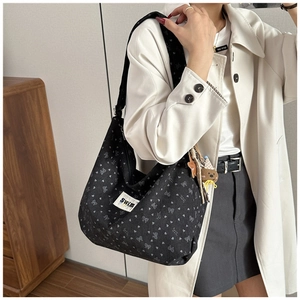 Detail showing a black corduroy bag with heart and bow prints and a cute bear charm