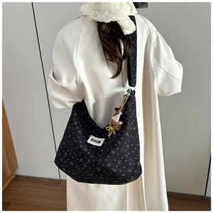Detail view of black corduroy tote with heart patterns and cute brown bear pendant
