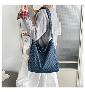 Detail of blue plaid tote bag showing soft fabric texture and wide shoulder strap