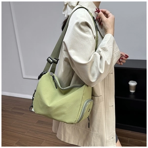 Detalle de bolso bandolera de lona verde ligera con correa ajustable sobre el modelo