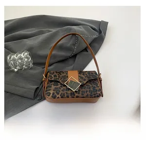 Detailed close-up of leopard print shoulder bag with gold buckle and smartphone for scale