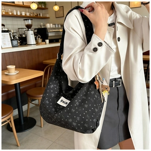 Close-up of black corduroy bag with grey bows and a cute brown bear charm