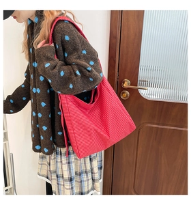 Detail view of large red plaid tote bag worn over the shoulder for casual retro style