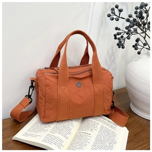 Close-up of orange-brown waterproof nylon Boston bag with multi-compartment zippers and straps