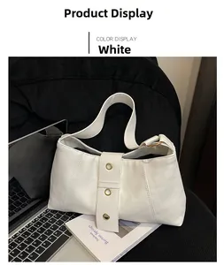 Close-up of white leather shoulder bag with stylish gold eyelet rivets on wide strap