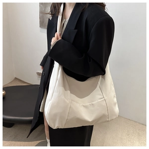 Gros plan d'un sac cabas crème avec surpiqûres géométriques sur tissu satiné lisse