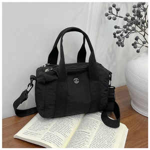 Detail of black canvas tote bag with M logo, adjustable strap and silver hardware
