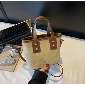 Détail du cabas en toile et cuir marron avec clous dorés sur un fond de bureau lifestyle