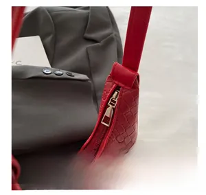 Detail view of the smooth golden zipper and woven texture on this red underarm bag
