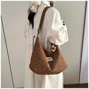 Brown canvas shoulder bag with heart print and cute bear plush charm shown on model