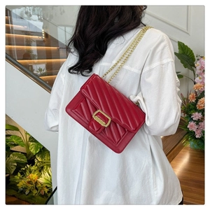 Detail of red quilted chain crossbody bag showing golden buckle and V-shaped texture