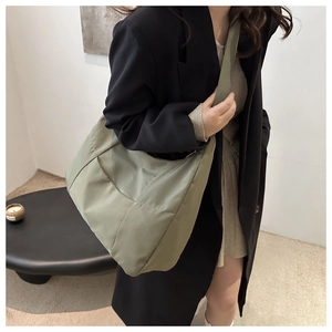 Détail d'un grand sac fourre-tout vert sauge minimaliste en forme de lune porté à l'épaule