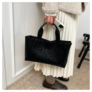 Close-up of leopard pattern tote bag in velvet fabric with model holding the handles
