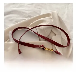 Détail de la boucle dorée ajustable et de la bandoulière en cuir rouge foncé du sac