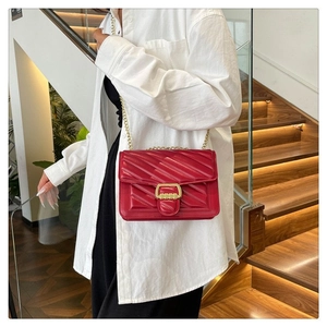 Detail of red quilted chain bag with V-shaped stitching and golden metal clasp lock