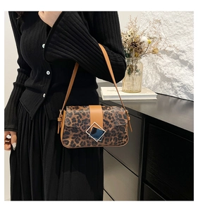 Close-up of leopard print shoulder bag with brown leather strap and square metal buckle