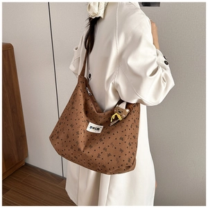 Close-up of brown corduroy tote with heart patterns and plush bear keychain detail