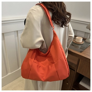 Vue détaillée du sac fourre-tout orange vif avec bandoulière réglable porté par un modèle