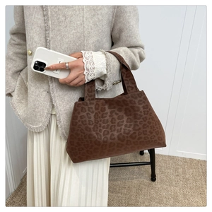 Detail view of large leopard print tote bag with brown velvet texture held by a model