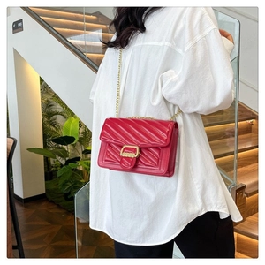 Detail of red quilted faux leather crossbody bag with elegant gold chain strap