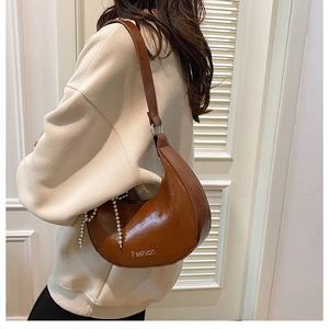 Detail view of brown wax leather shoulder bag with fashion print and silver bead chain