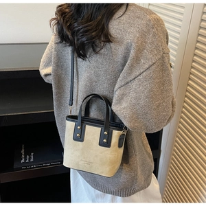 Détail du sac seau contrasté en daim beige avec des finitions en cuir noir élégant