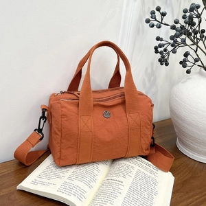 Orange washed canvas crossbody bag with dual zippers and circular metal M logo