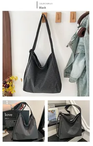 Detail of vintage black and white plaid canvas hobo bag on a wall hook and handheld