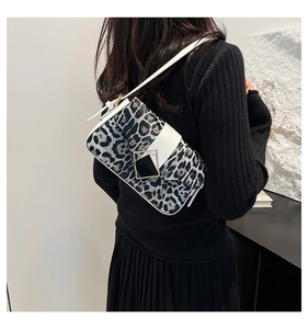 Detailed side view of leopard print shoulder bag with white leather strap and buckle
