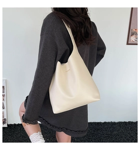 Detailed shot of cream white faux leather tote bag with FASHION logo on a female shoulder