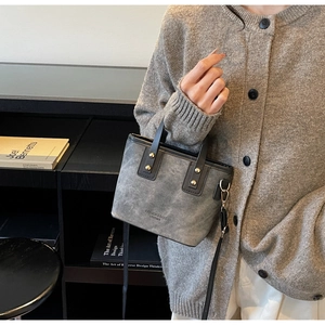 Détail du sac à bandoulière en daim gris avec poignées en cuir noir et rivets dorés