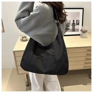 Vue arrière détaillée d'une personne portant un grand sac cabas noir minimaliste en nylon