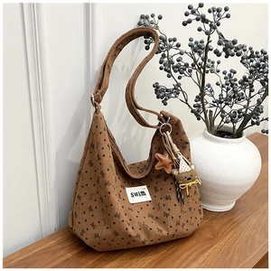 Detail of brown corduroy tote bag featuring bow patterns and cute bear charm pendant