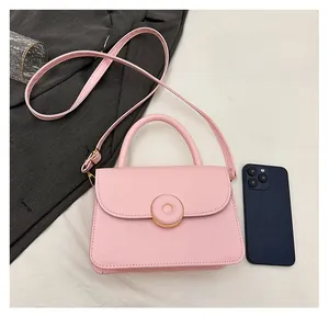 Pink minimalist crossbody bag shown next to a smartphone for size comparison