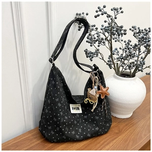 Detail of black corduroy tote bag with heart prints and cute bear star pendant