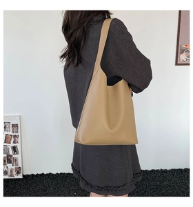 Lifestyle shot of khaki oversized tote bag worn by model against minimalist background