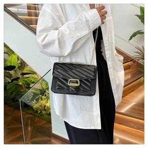 Detail shot of black quilted crossbody bag with gold chain and buckle on model