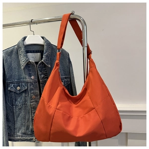 Détail du tissu en nylon orange vif avec texture plissée et large bandoulière souple