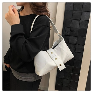 Close-up of a white leather underarm bag with metal rivets and stylish shoulder strap