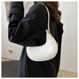 Detail shot of the white woven texture and crescent shape of this minimalist underarm bag