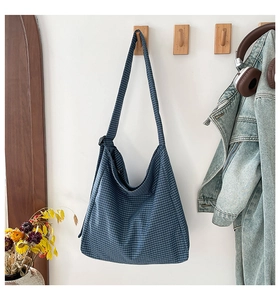 Detail of blue checkerboard canvas hobo bag hanging on a hook in a lifestyle setting