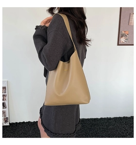 Side view of khaki faux leather tote bag with FASHION print on a model in minimal setting